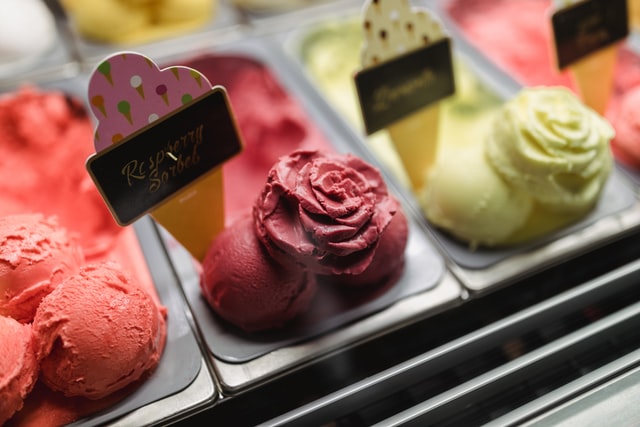 Containers of ice cream with sample scoops at the edge of each one shaped like flowers.